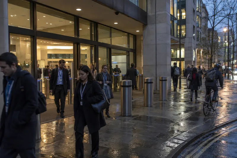 People outside a lit office building at dusk
